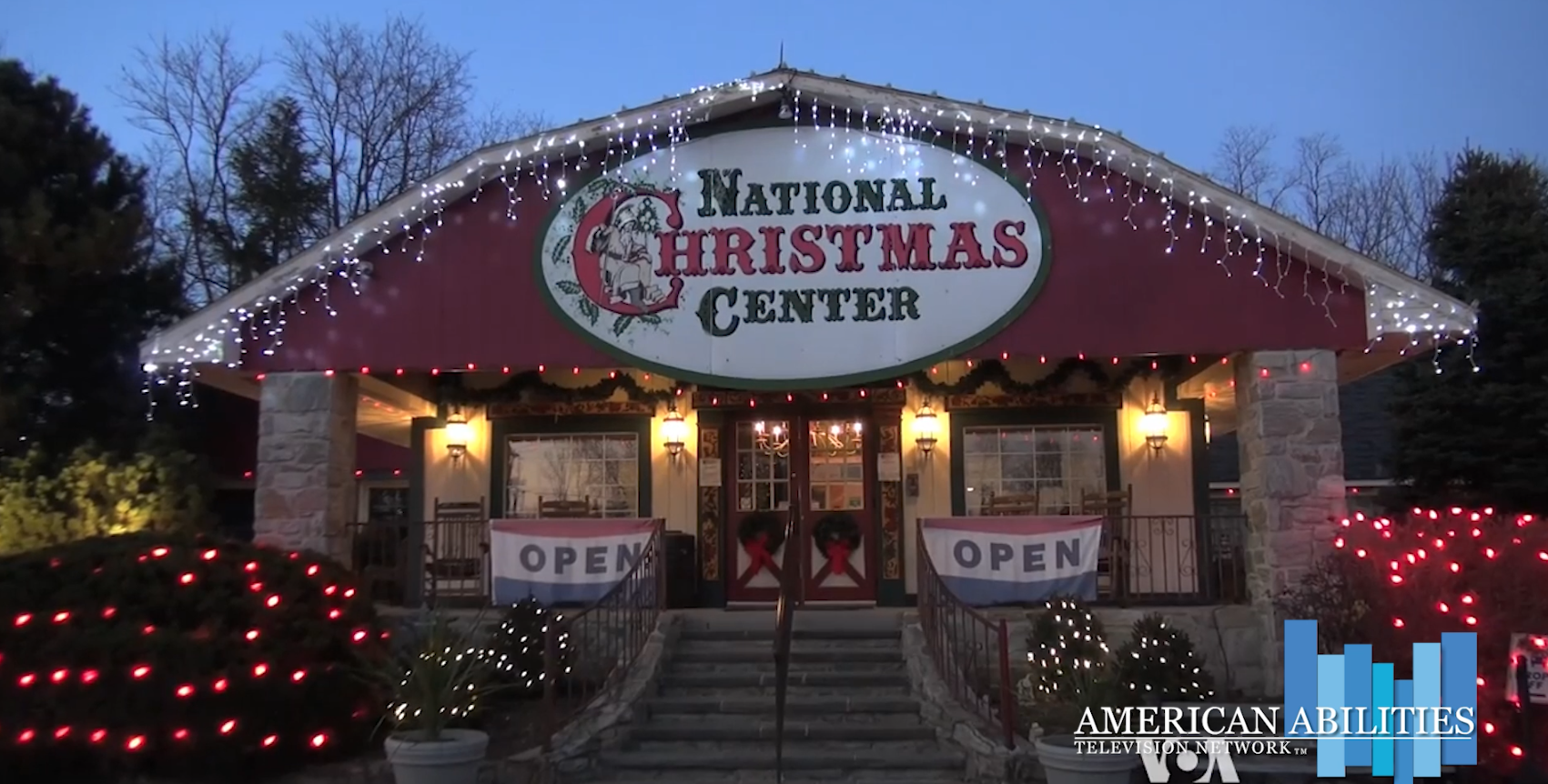 The National Christmas Center building at dusk, its oval sign and doorway glowing with strings of lights, in a still from the Christmas Museum Evokes Memories of Holidays Past segment