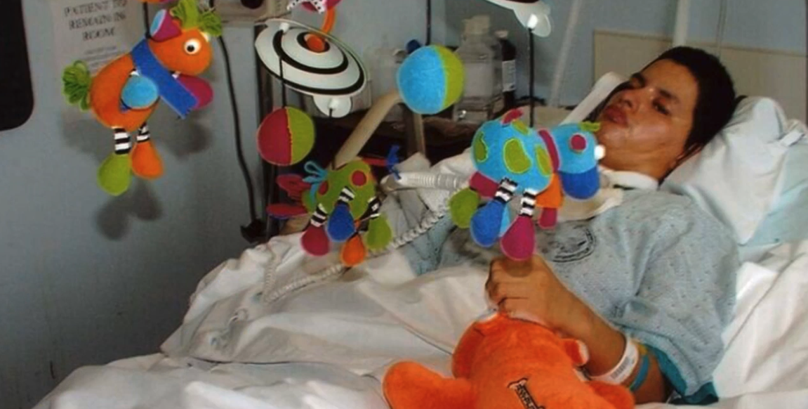 A woman veteran recovering in a hospital bed surrounded by colorful gifts