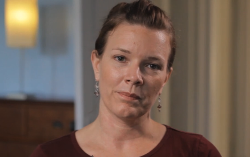 CPT Sarah Humphries, a woman in a dark red top, seated for an interview in a home setting, in a still from About PTSD symptoms — AboutFace, VA National Center for PTSD